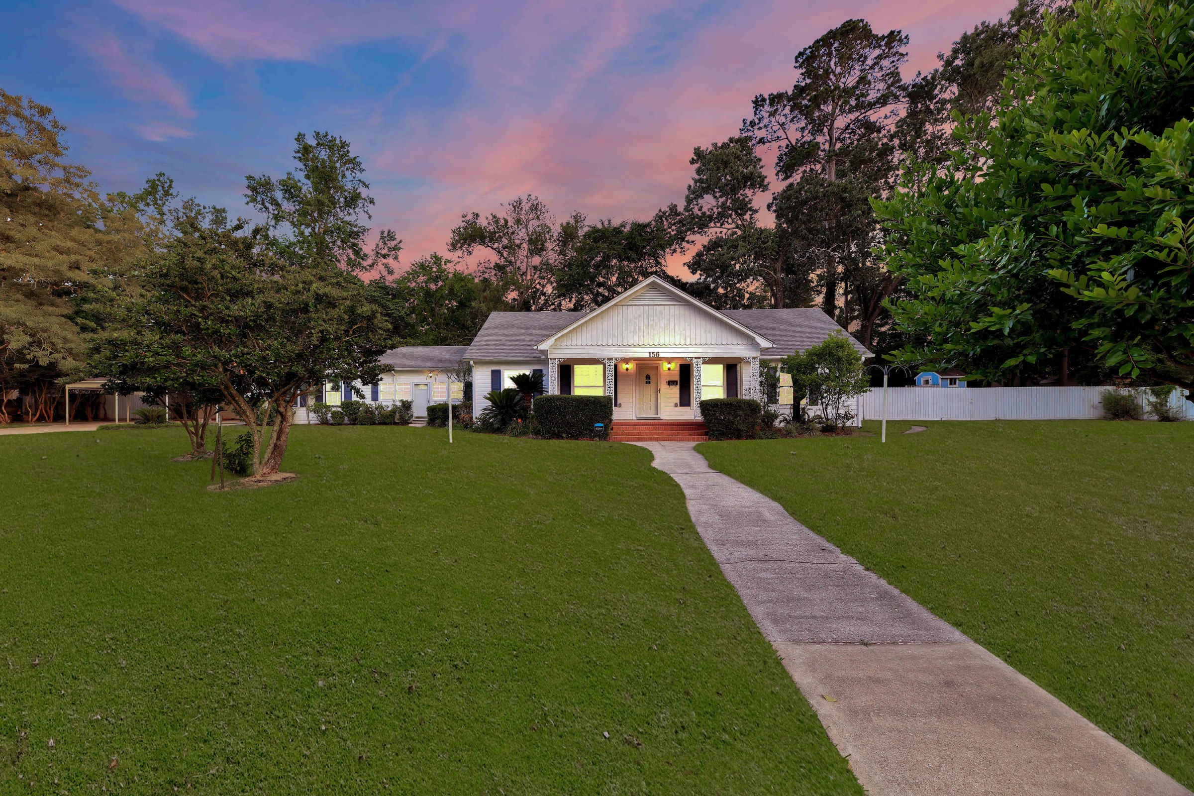 Twilight exterior of a white home with a wide lawn
